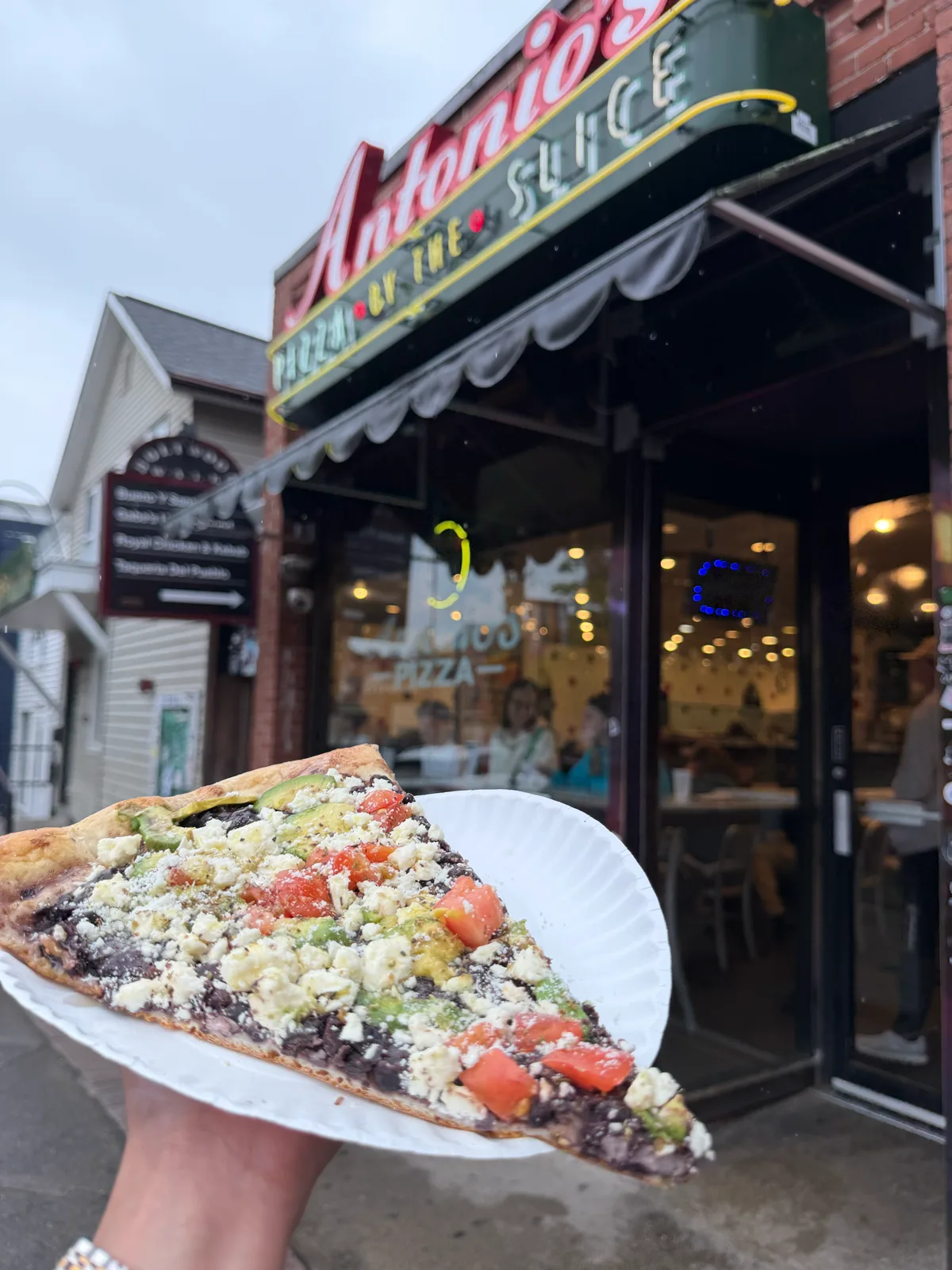 Specialty slice topped with feta and fresh tomato at Antonio's Pizza Amherst