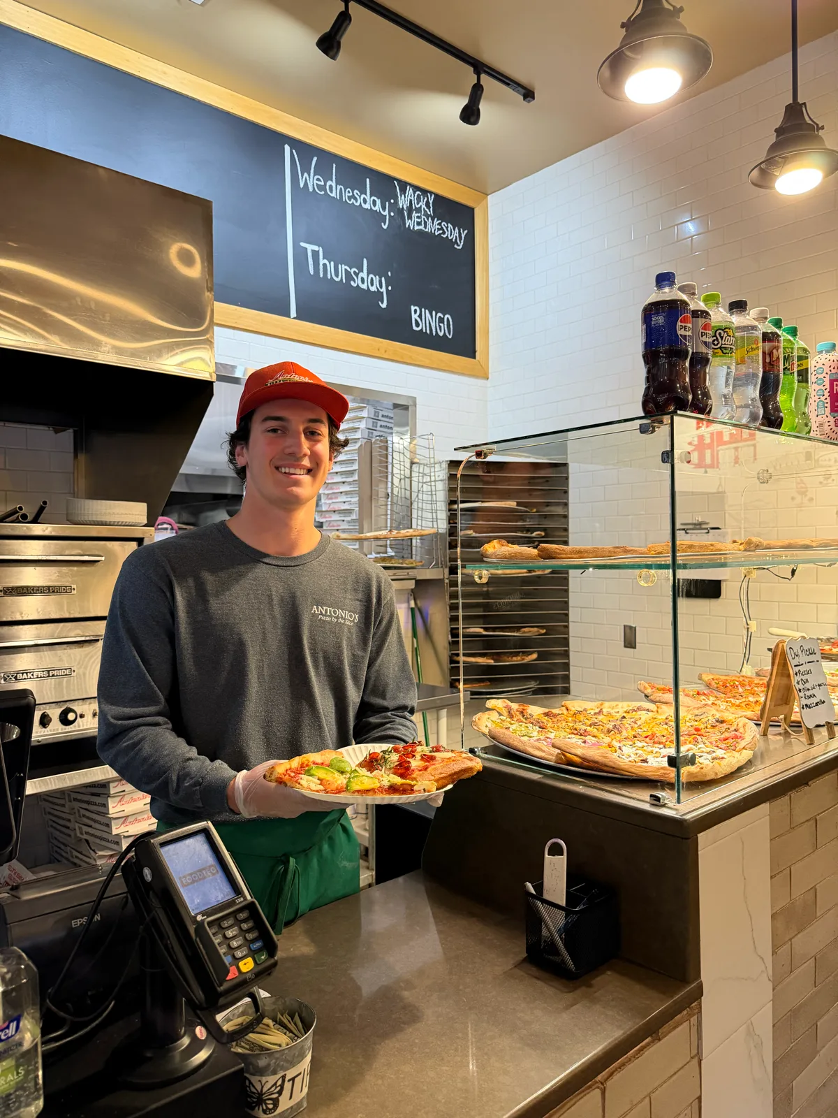 Antonio's Pizza Belchertown team member with a fresh slice at the counter