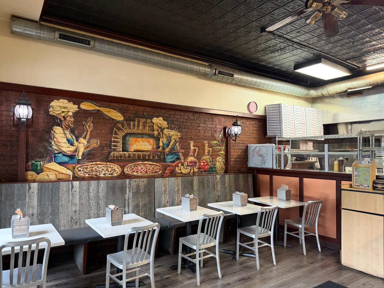 Dining room seating beneath the brick-oven pizzaiolo mural at Antonio's Easthampton