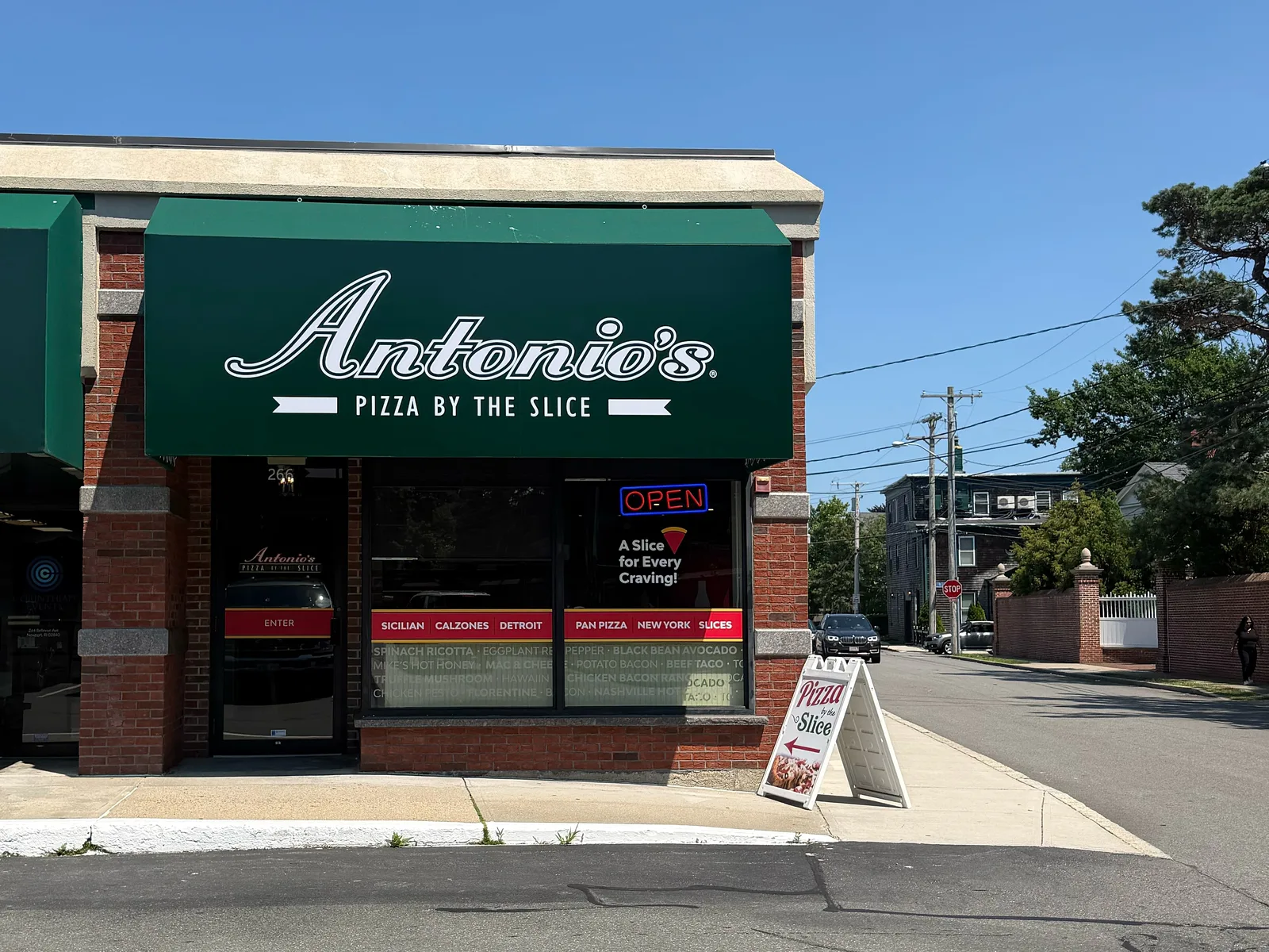 Antonio's Pizza by the Slice storefront at 266 Bellevue Avenue, Newport, with its green awning under a clear sky