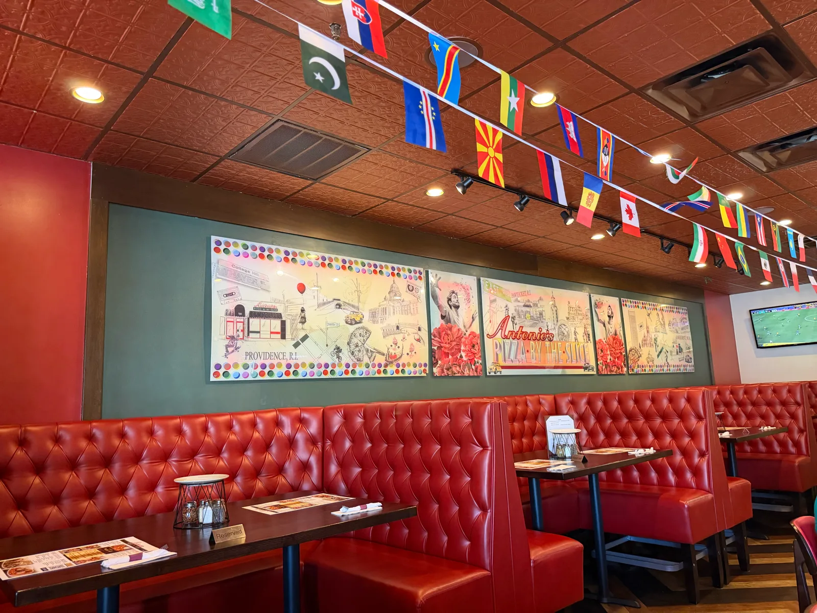Red booth dining room with the Providence mural and world flags at Antonio's Pizza Pawtucket