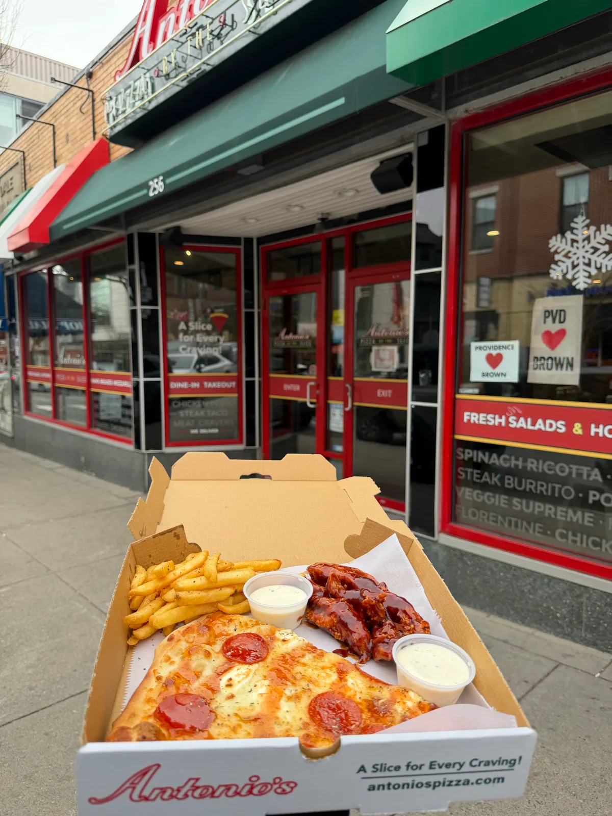 Pizza, wings and fries in an Antonio's box outside the Thayer Street shop
