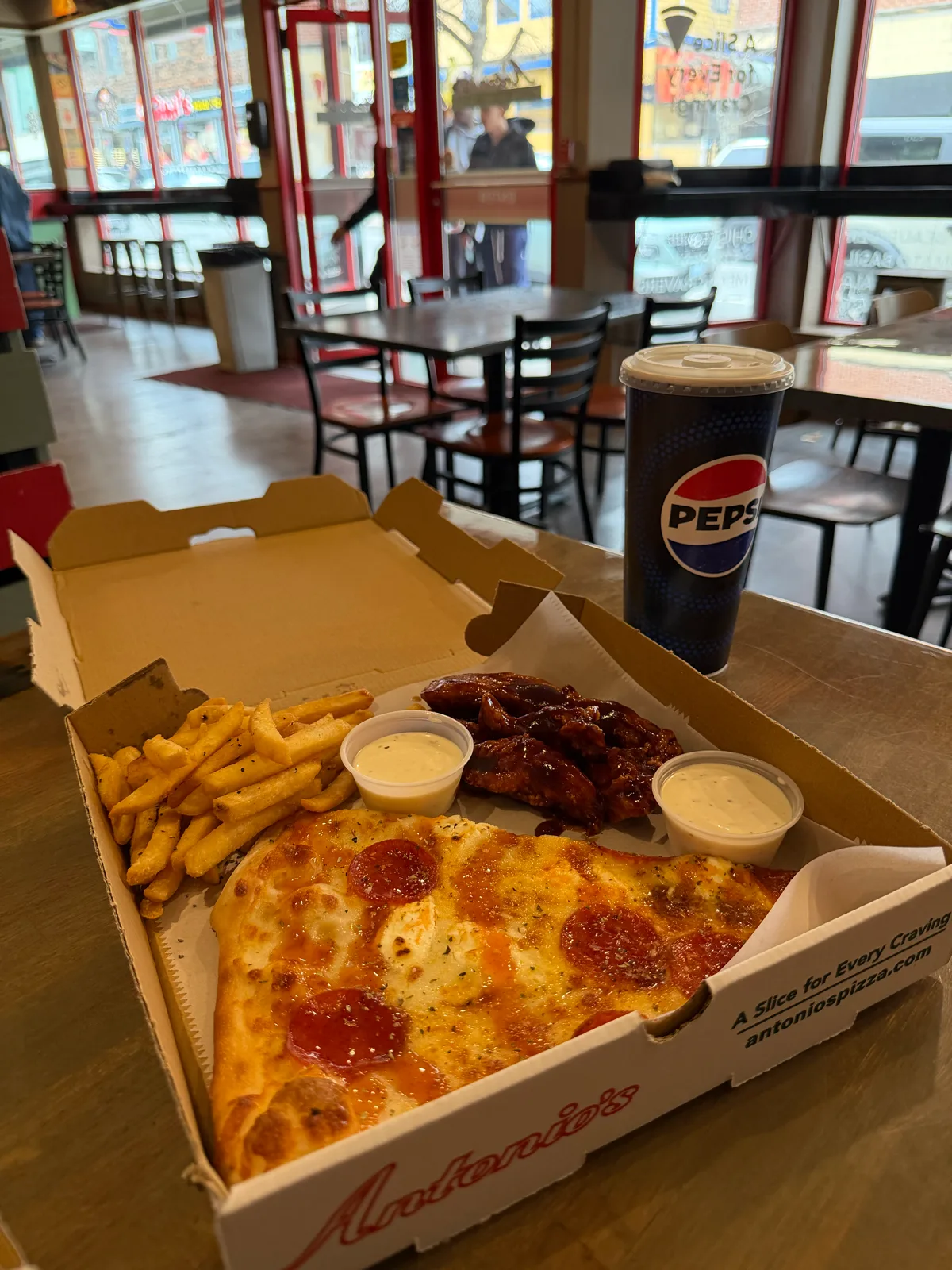Pepperoni slice with wings and fries in the Thayer Street dining room