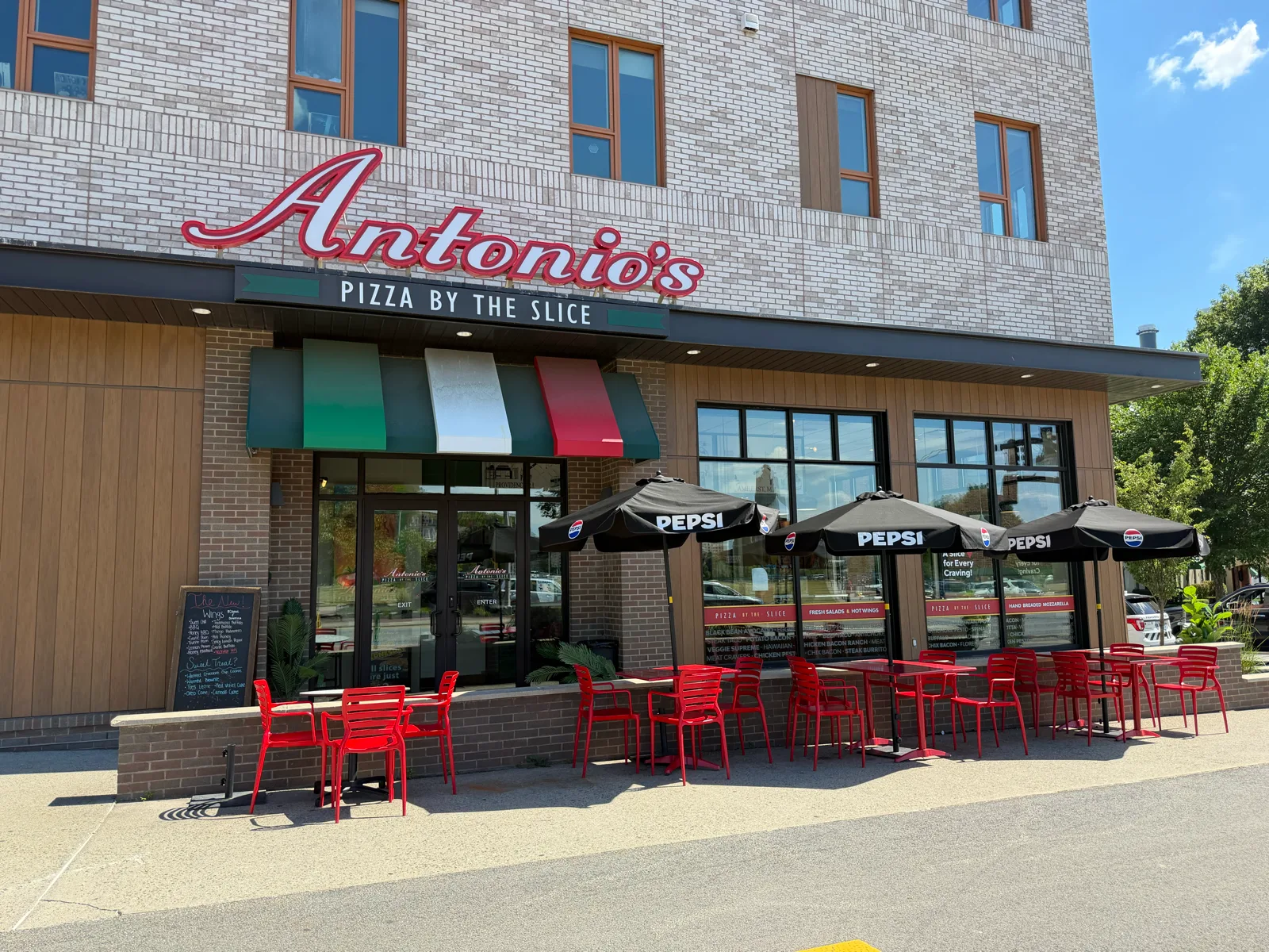 Antonio's Pizza by the Slice on Wickenden Street - storefront by day with red patio seating