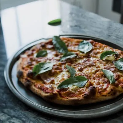 Antonio's pizza with basil on a black tray