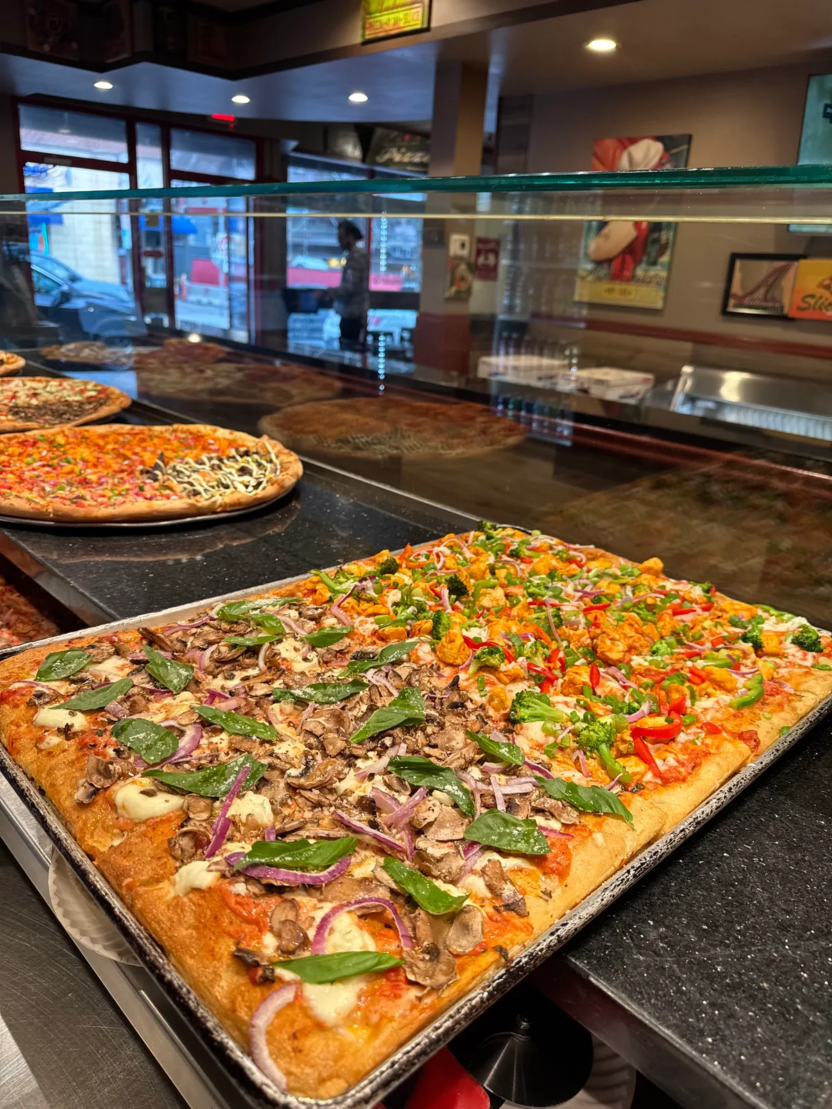Antonio's Sicilian tray pizza with spinach and mushrooms in the display case