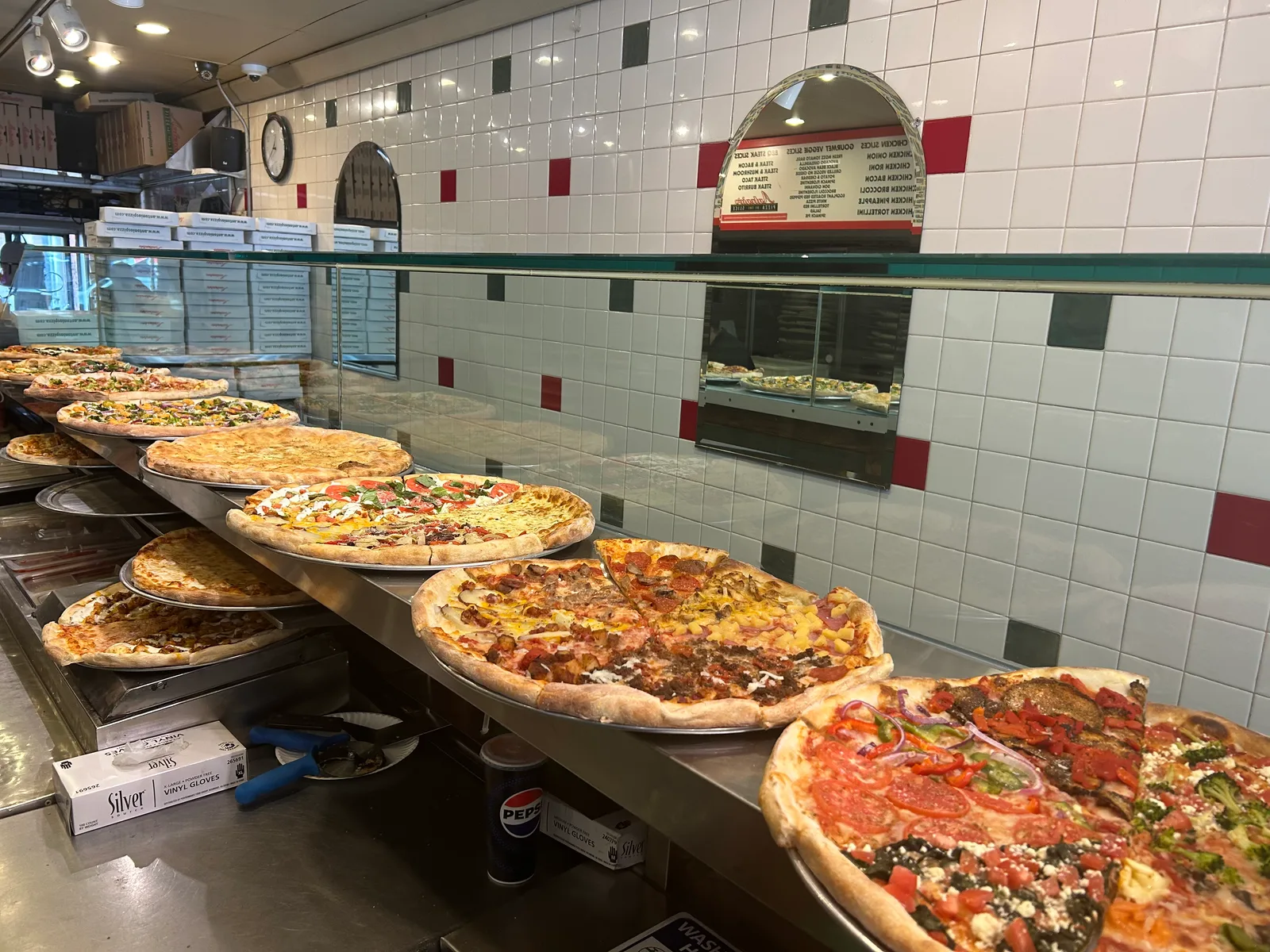A long counter lined with whole Antonio's pizzas under classic white tile